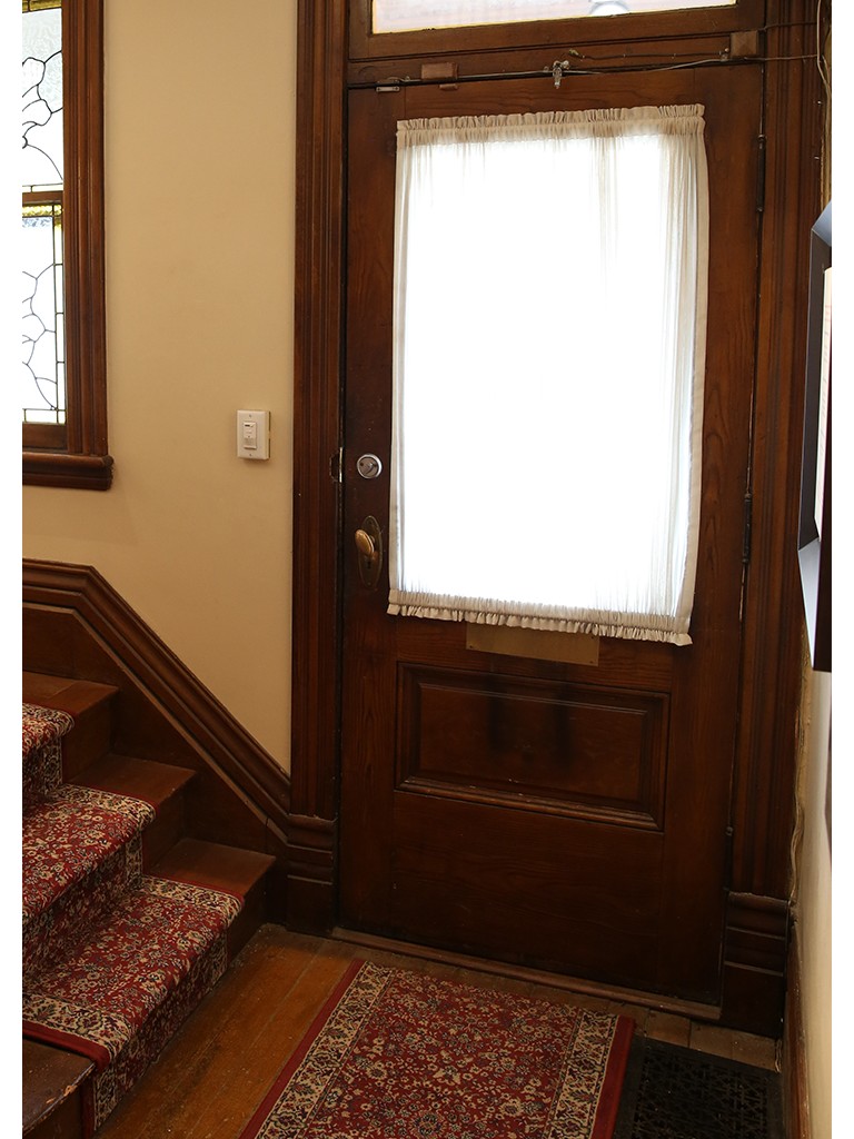 Wooden front door with white cloth curtain