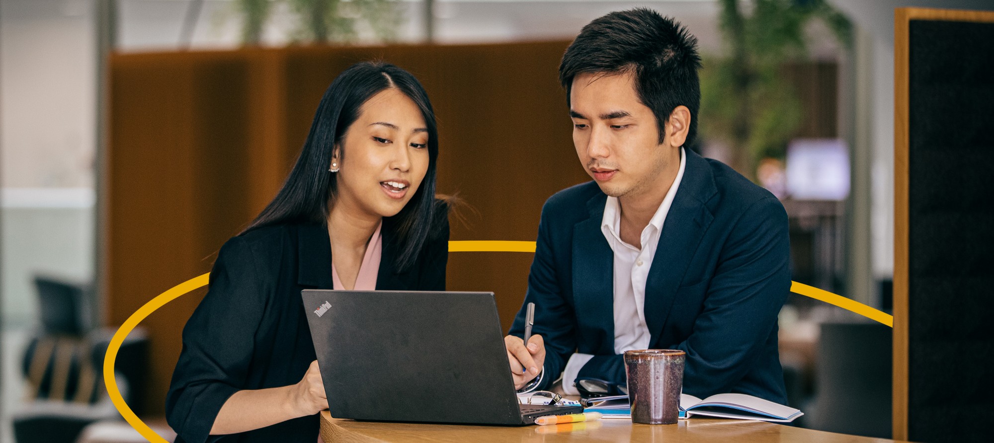 A man and woman are collaborating at a desk with a laptop