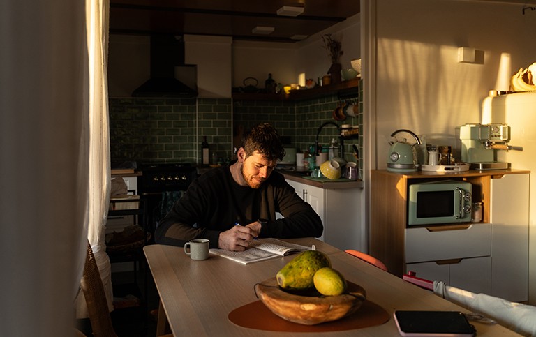 A man writing in his planner at the kitchen table