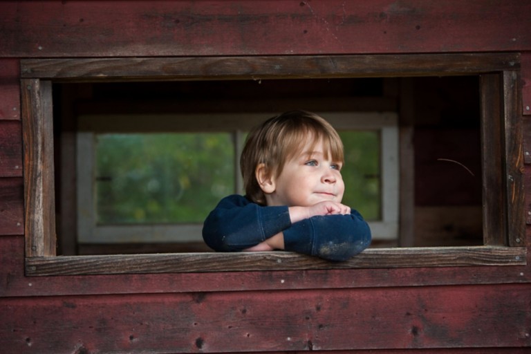 A child leans on a wooden windowsill