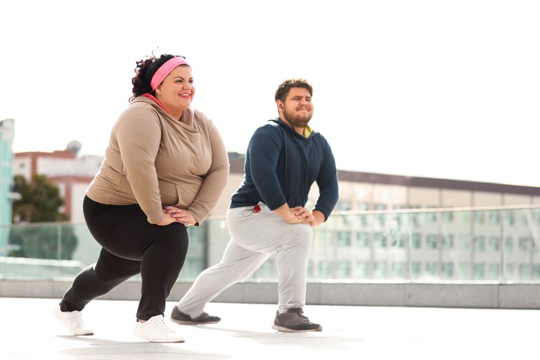 Two overweight adults exercising in athletic clothing