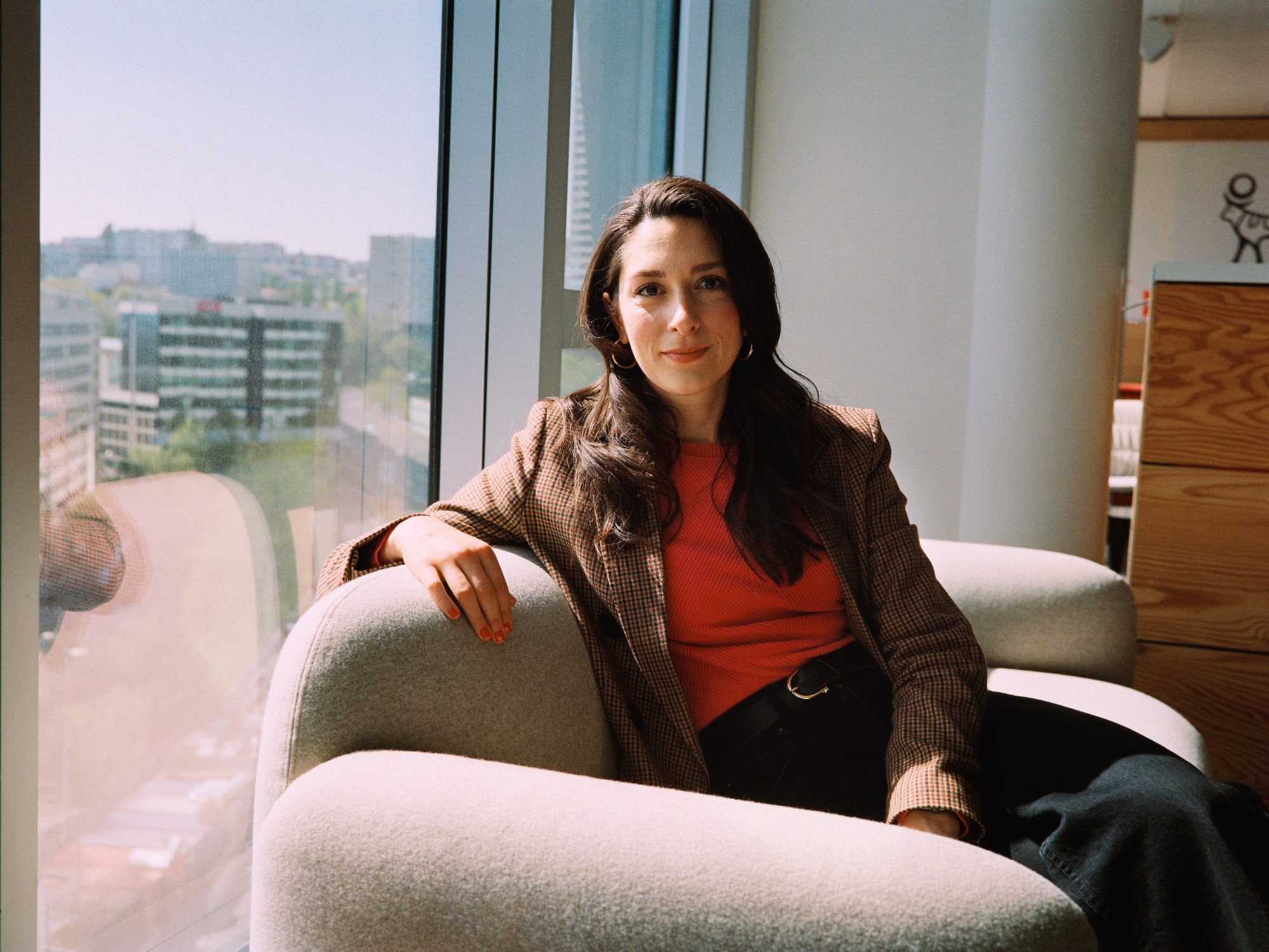 Lola est assise sur un fauteuil à côté d'une fentre au soleil. 