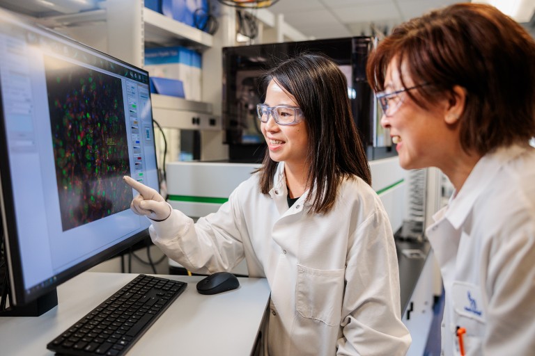 Two women examining scientific models on a computer monitor