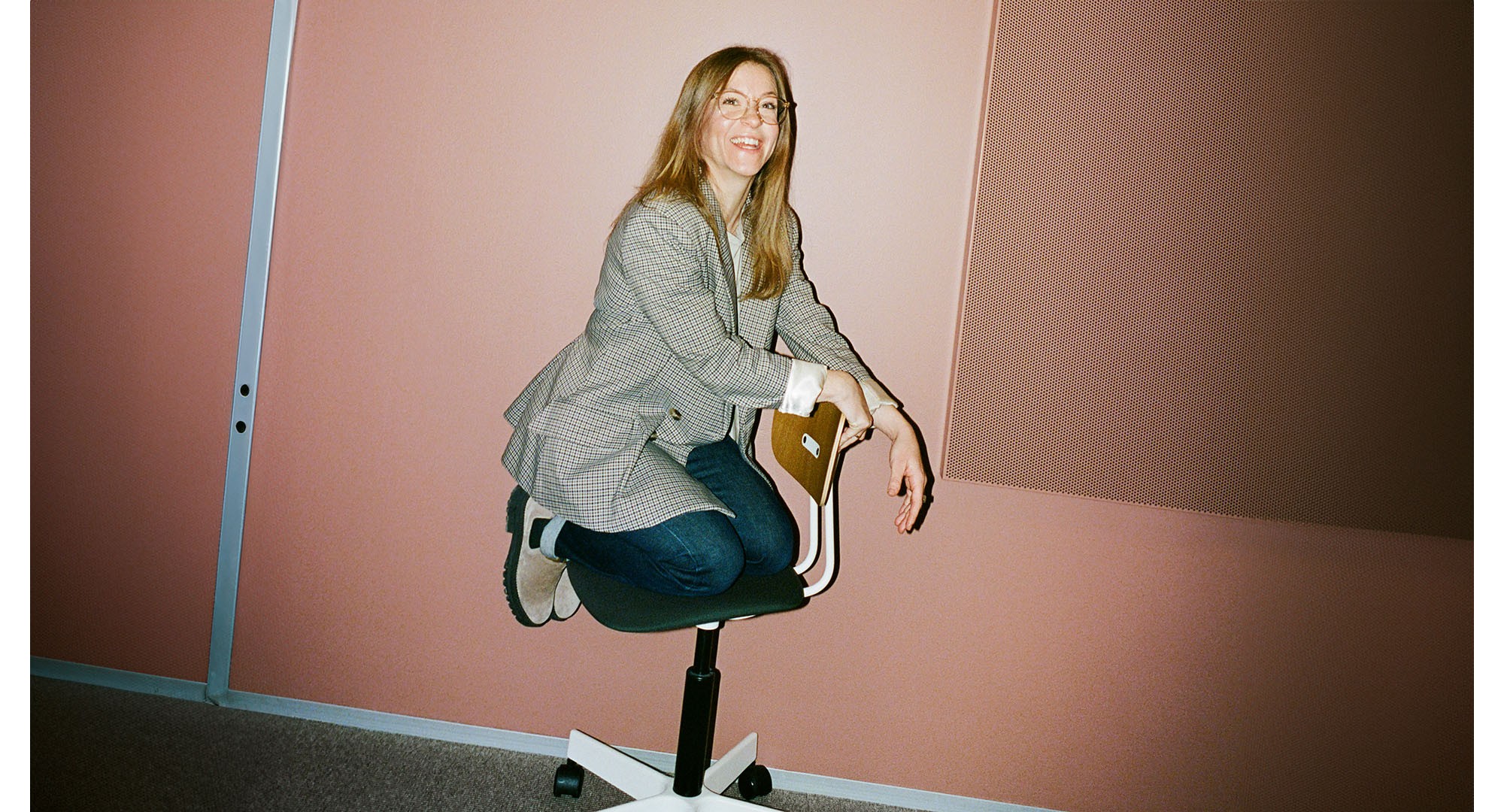 One of our colleagues kneeling on a chair and talking about what it means for them to work at Novo Nordisk