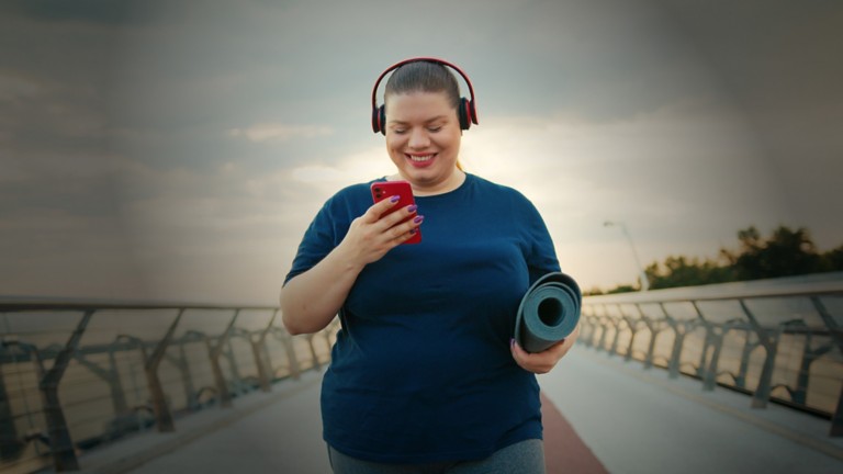 An obese woman looking at her phone after exercising