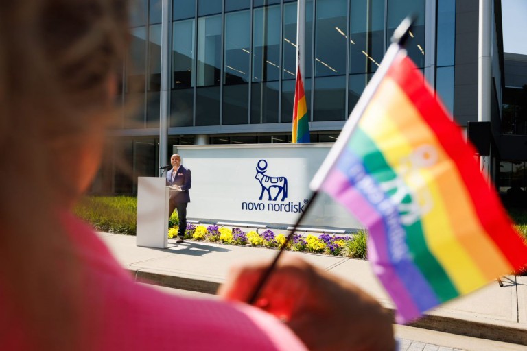 A pride flag waving in front of a Novo Nordisk building