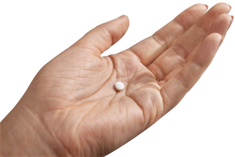 Image of a pill in the hand of a woman