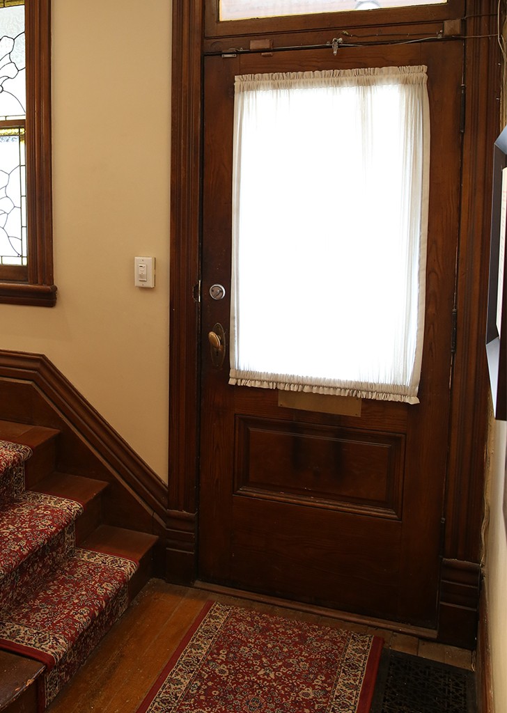 Wooden front door with white cloth curtain