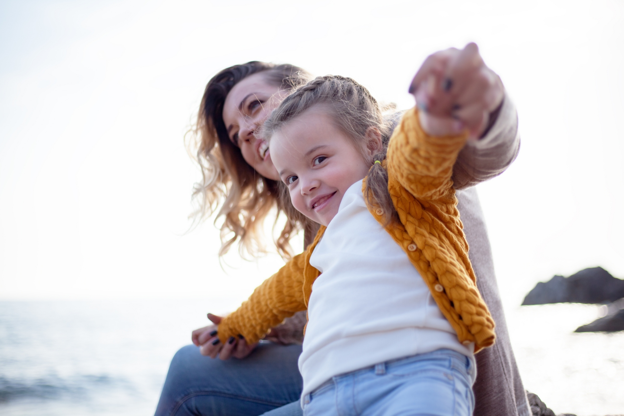 Happy family posing outdoor in the beach of the sea at spring time. woman with daughter have fun on vacation near ocean. Parent make hands - flying. Travel, love, holidays concept - lifestyle