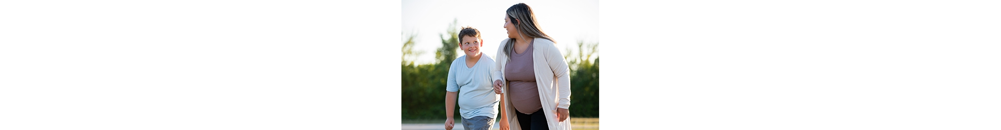 Young pregnant mom spends time outdoors with her preteen son jogging and playing with a soccer ball