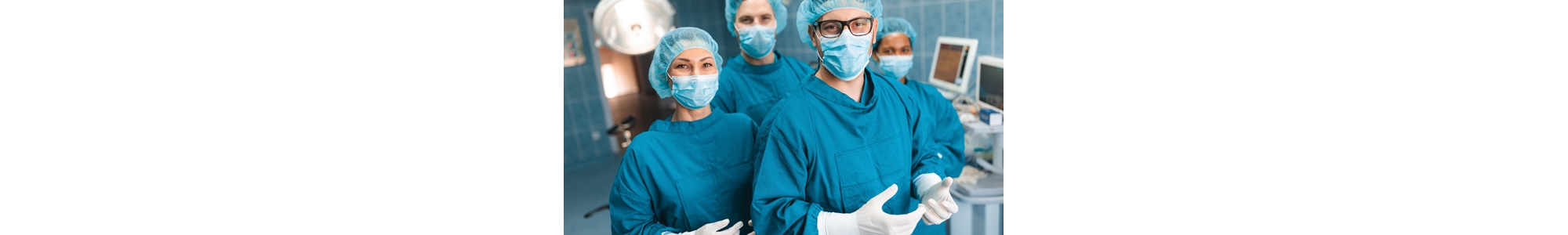 Group of medical professionals standing and looking at camera in operating room as they pose together for a portrait, dressed professionally in operating gowns, wearing surgical masks, caps and gloves