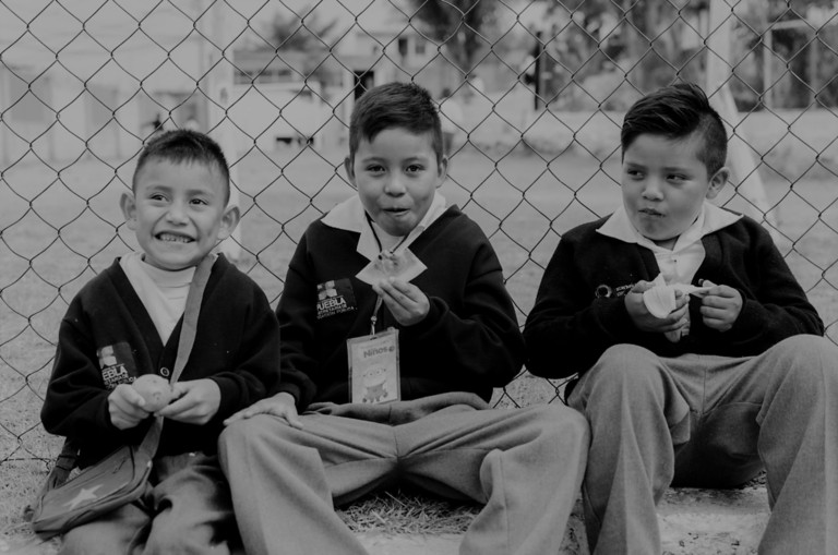Three children wearing school uniforms eating lunch