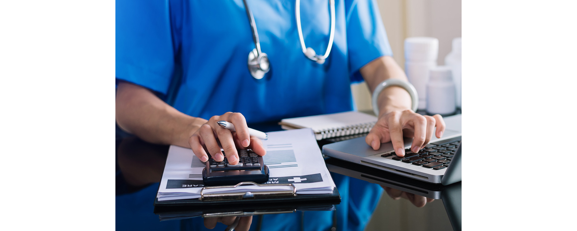 Healthcare costs and fees concept.Hand of smart doctor used a calculator and smartphone, tablet for medical costs at hospital in morning light