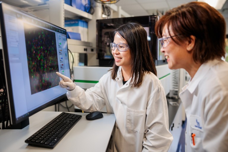 Photo of two researchers discussing data on a computer monitor