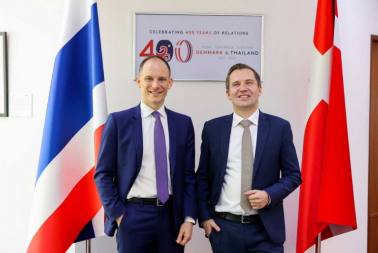 Image of a two males standing infront og flags